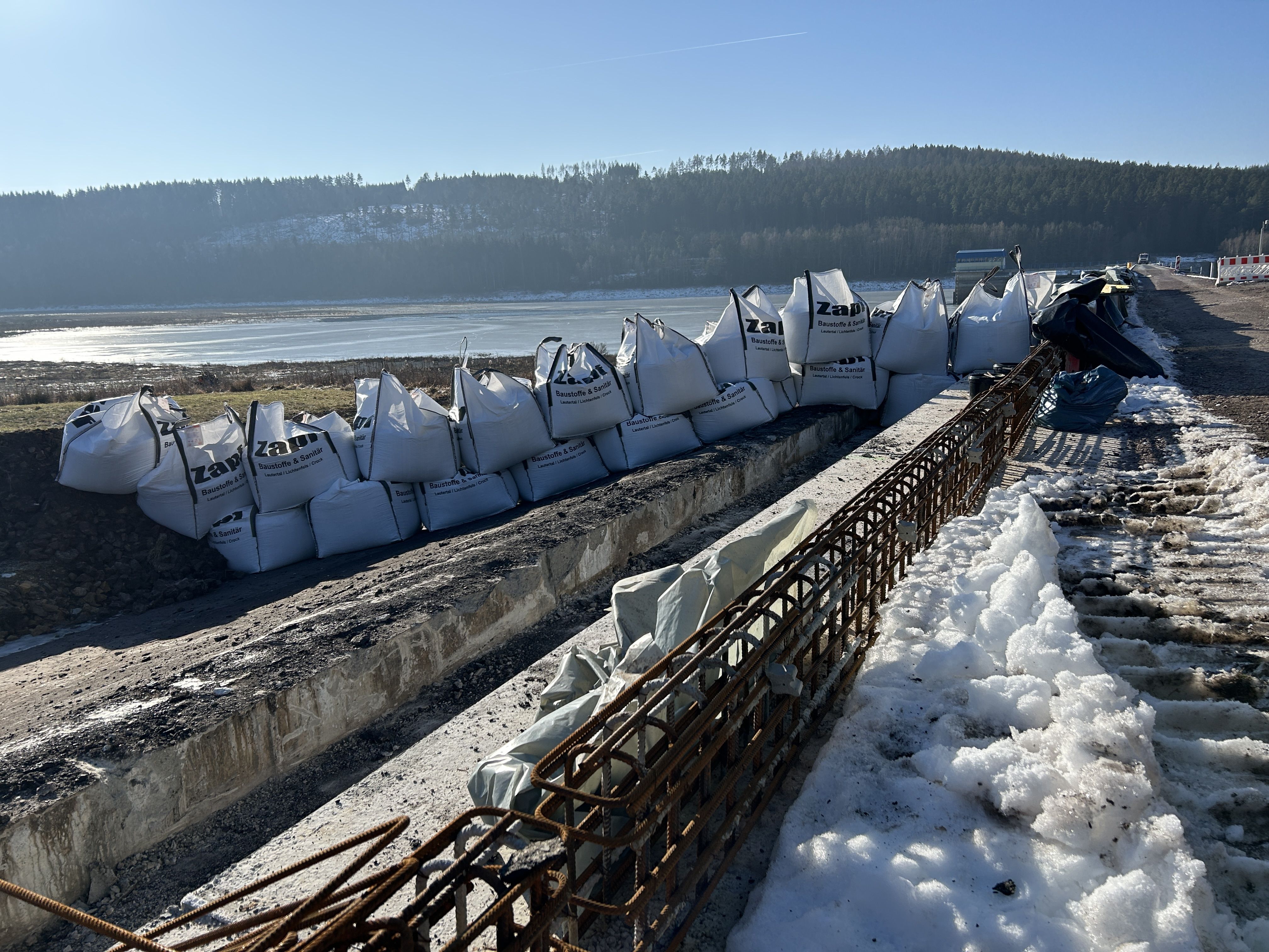 Bewehrung entlang des Damms, der Baustellenbereich ist mit Sandsäcken gesichert udn auf dem Damm liegt noch Schnee