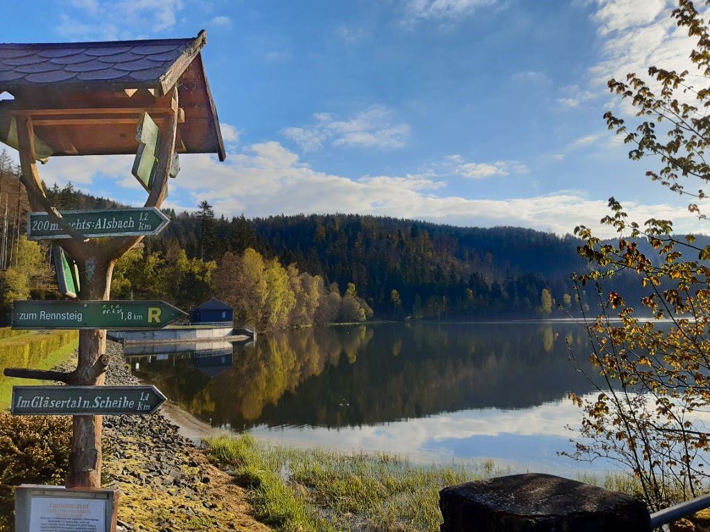 Blick auf den Stausee der Talsperre Scheibe-Alsbach, im Vordergrund ein hölzernes Wanderschild