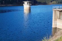 Blick auf den gefüllten Stauraum der Talsperre, in der Mitte ist der Entnahmeturm zu sehen, dessen Laterne aus dem Wasser herausragt.