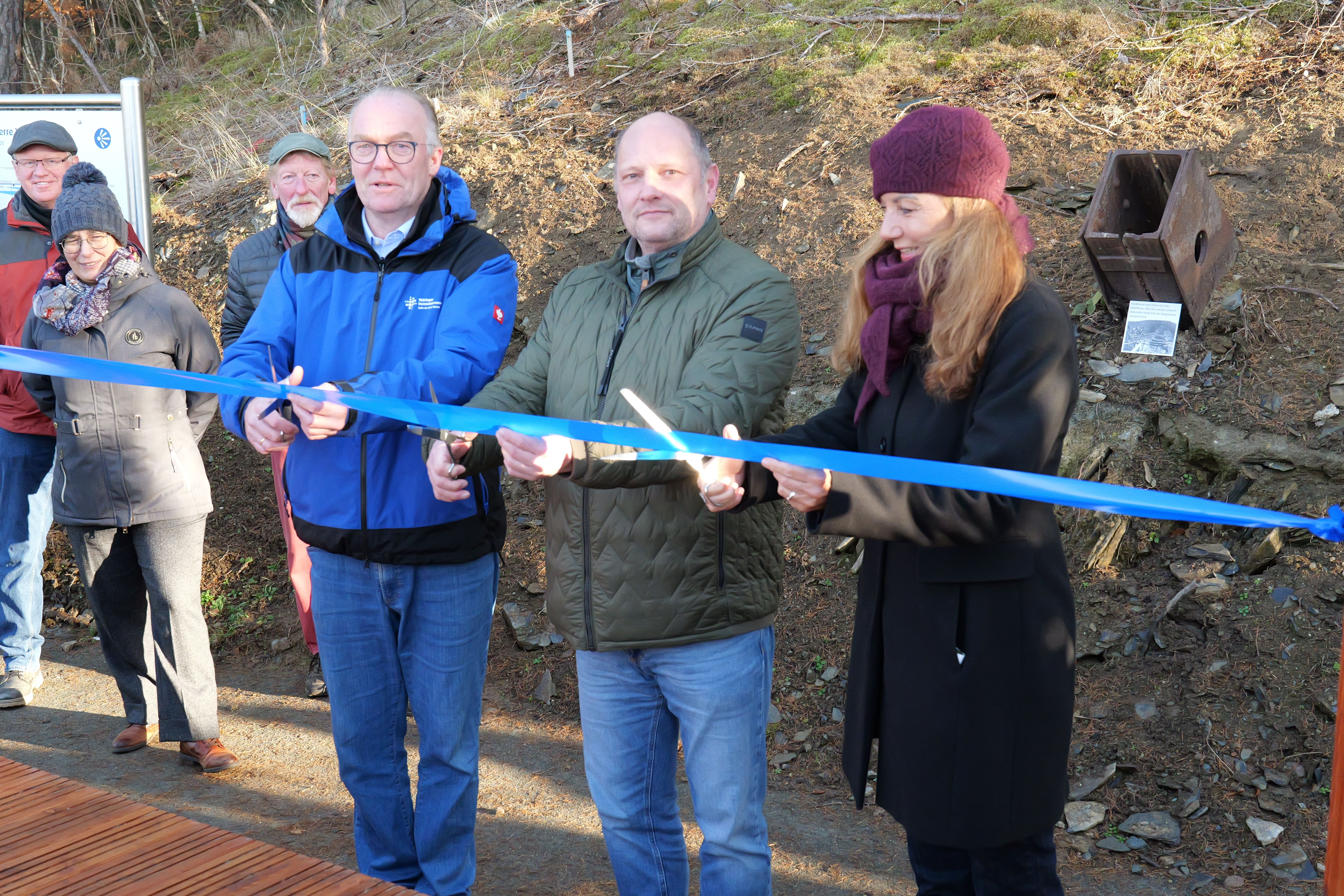 Drei Personen schneiden das Absperrband des Rundwanderwegs durch