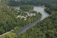 Luftblick auf den schlängelnden Stauraum mit einer kleinen Siedlung und am Uferbereich.