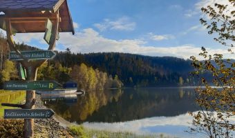 Blick auf den Stausee der Talsperre Scheibe-Alsbach, im Vordergrund ein hölzernes Wanderschild