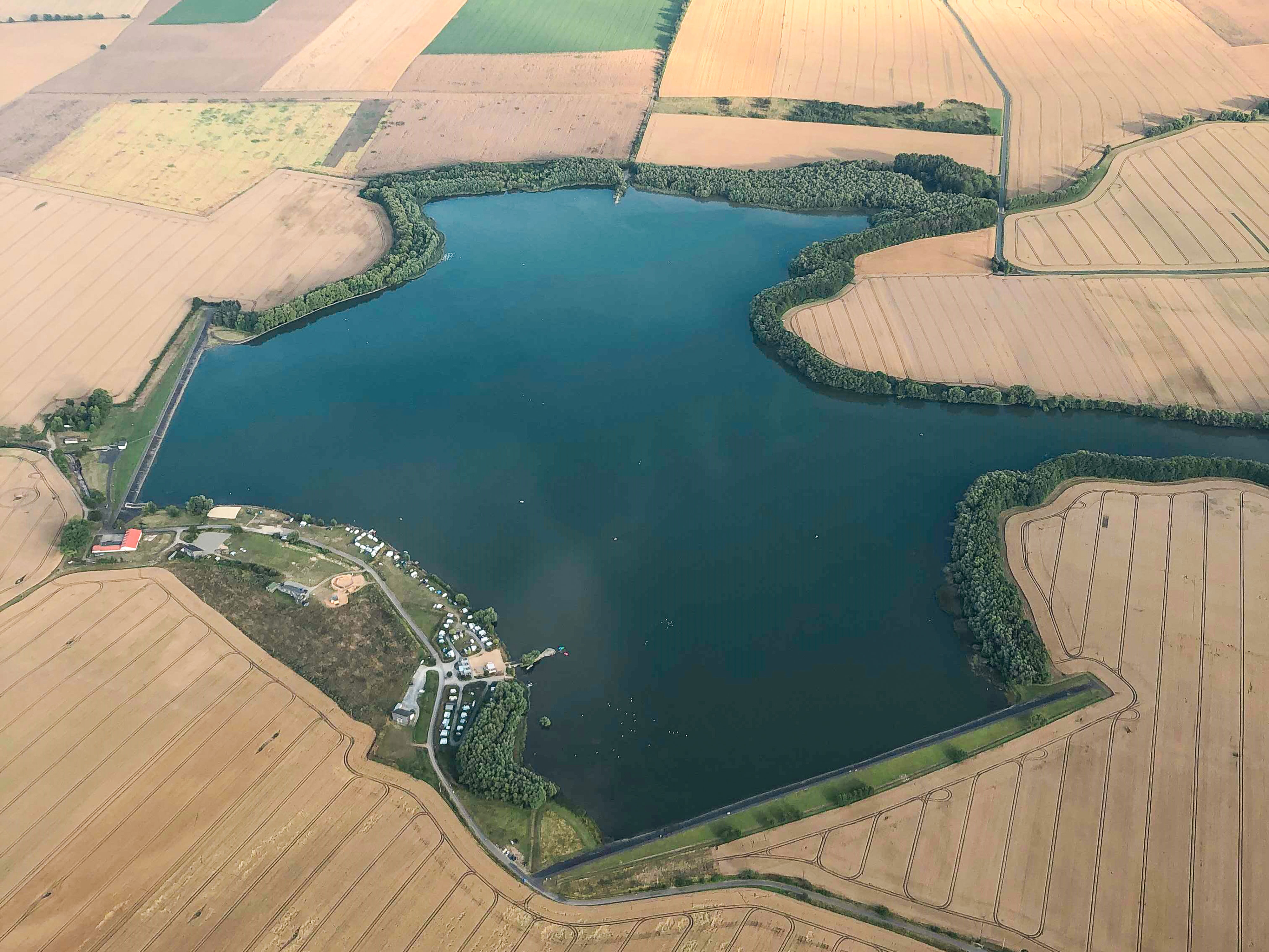 Luftaufnahme der Talsperre Seebach umgeben von landwirtschaftlichen Feldern