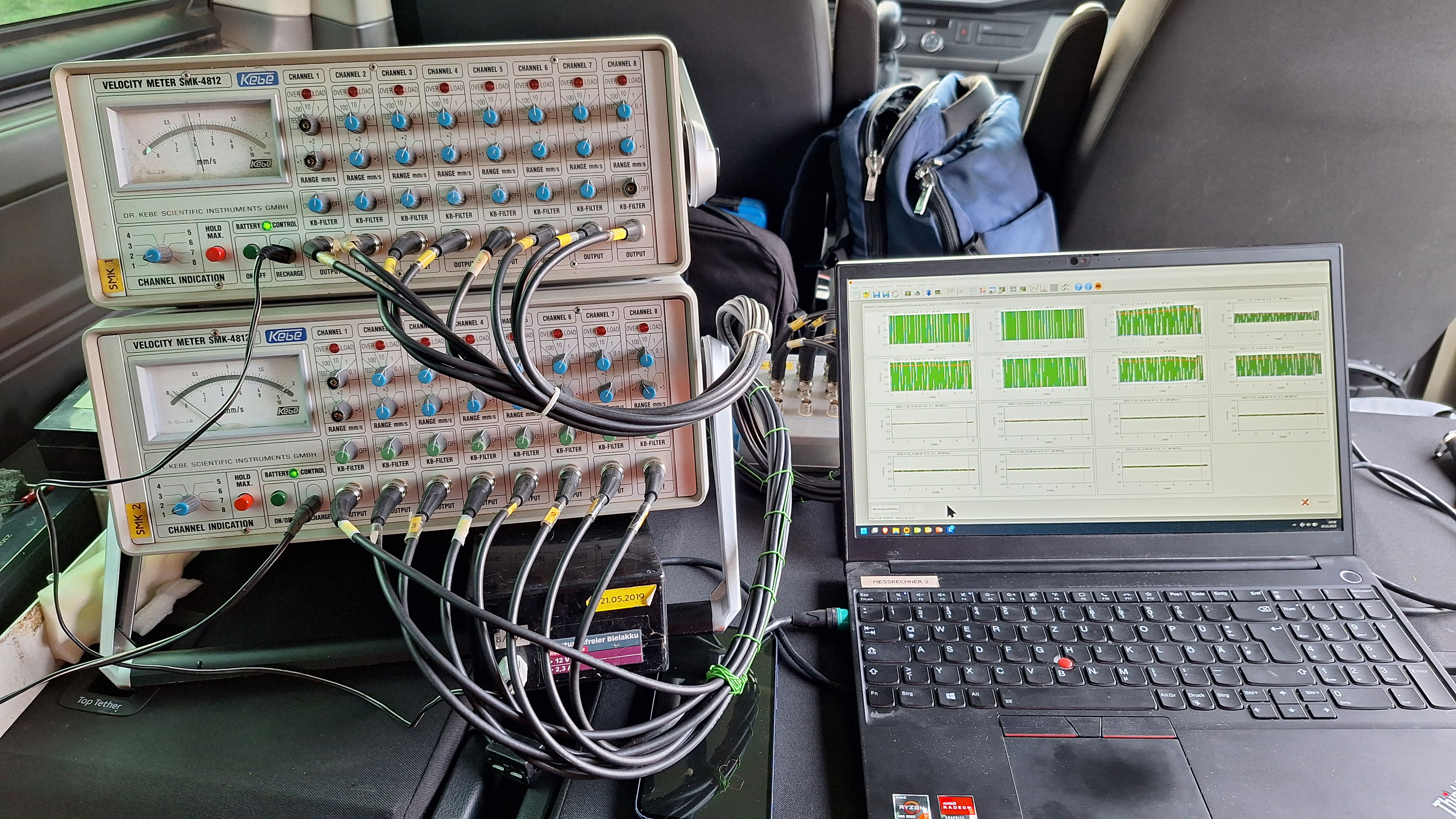 Innenraum eines Fahrzeugs mit PC und angeschlossenem Messgerät zur Erfassung von Erschütterungen im Probenfeld