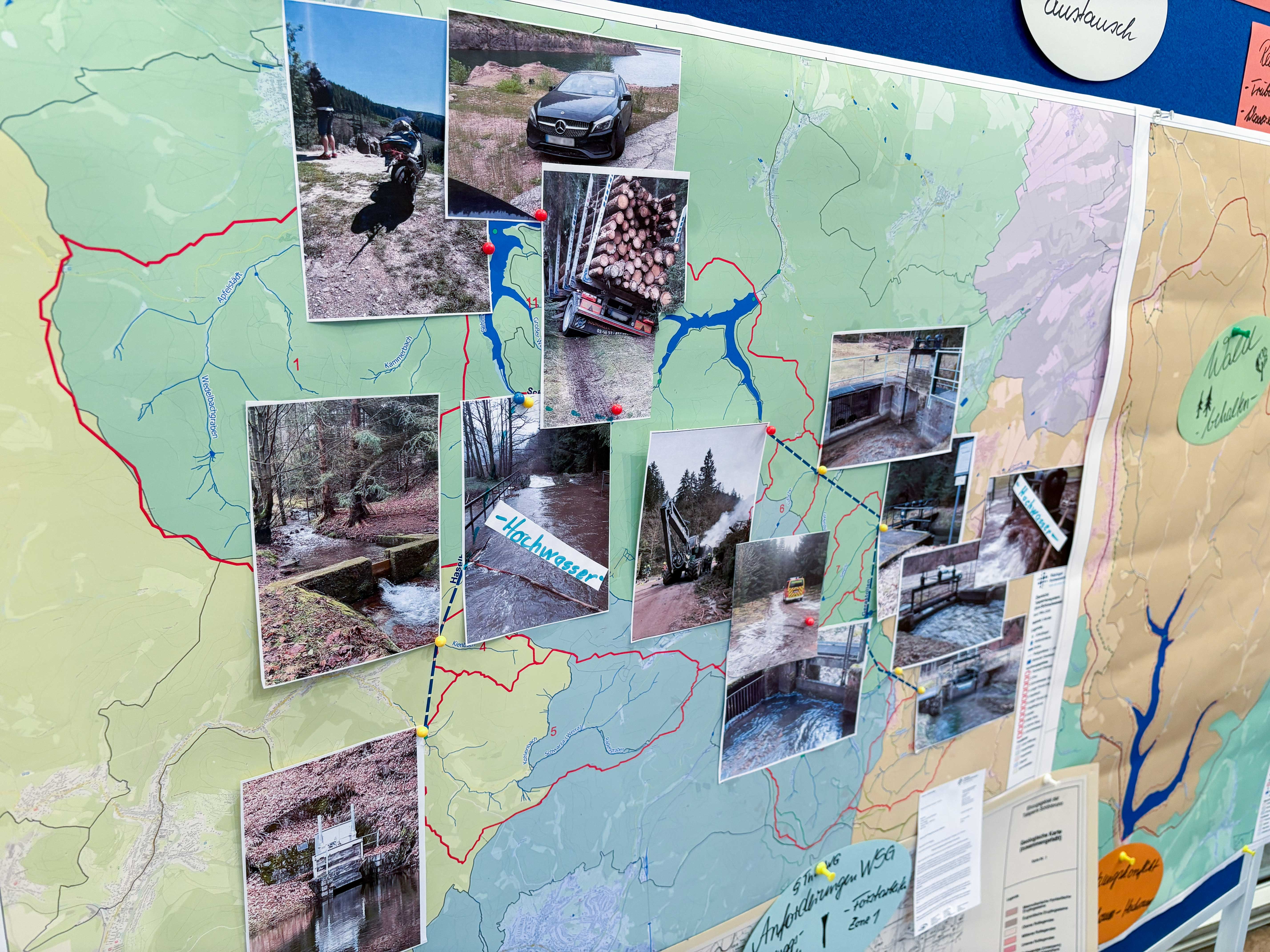 Eine Wandtafel mit einer Landkarte eines Trinkwasserschutzgebietes auf die Fotos aufgeklebt sind. Die Fotos zeigen unter anderem verunglückte Forstmaschinen und die Auswirkungen, welche diese auf die Waldwege und damit auf die Bodenerosion haben.