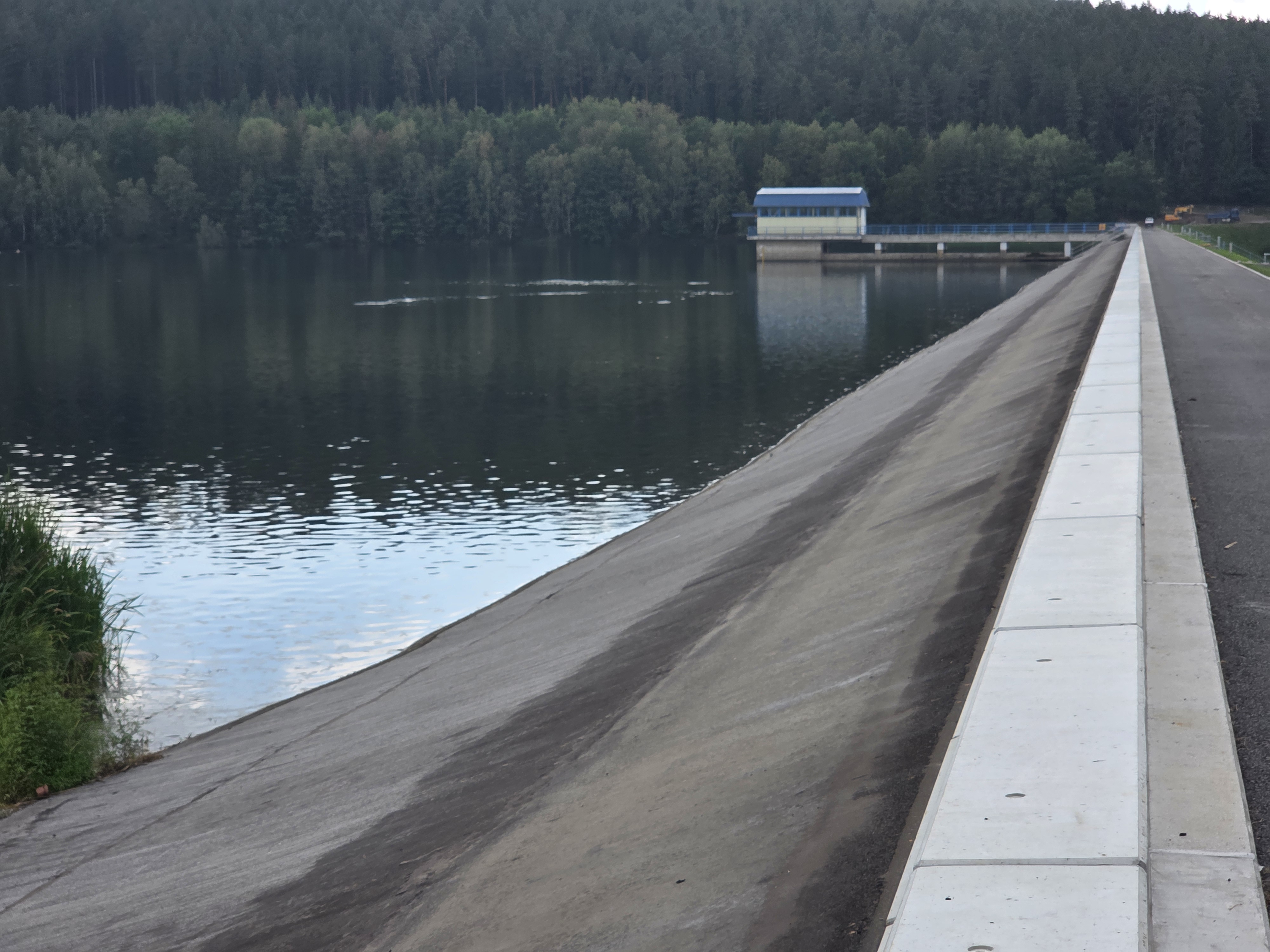 links im Bild ist die Wasserfläche zu sehen, daneben der Damm mit den neuen Wellenumlenkern. Im Hintergrund ist das Entnahmebauwerk im Wasser zu sehen.